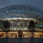 A futuristic, ship-shaped Louis Vuitton flagship store with a glass and steel facade reflects Shanghai’s skyline at dusk, illuminated by vibrant lights and surrounded by crowds.